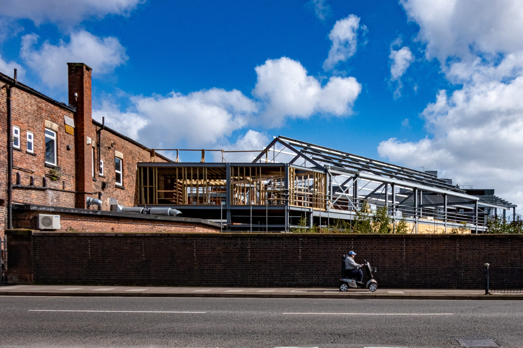 New steel frame construction behind a wall, mobility scooter passing