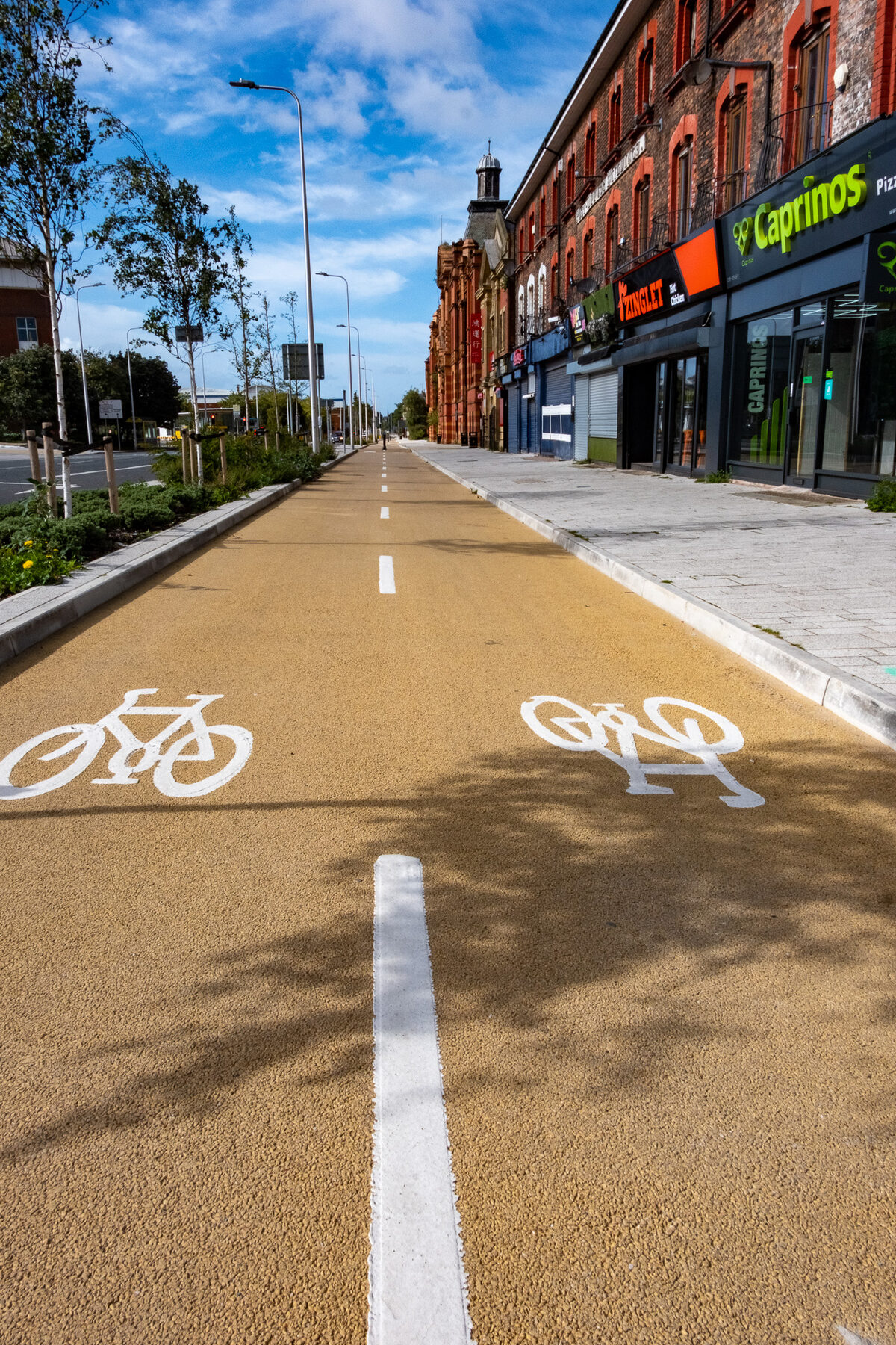 New orange cycle lane beside a shopping parade