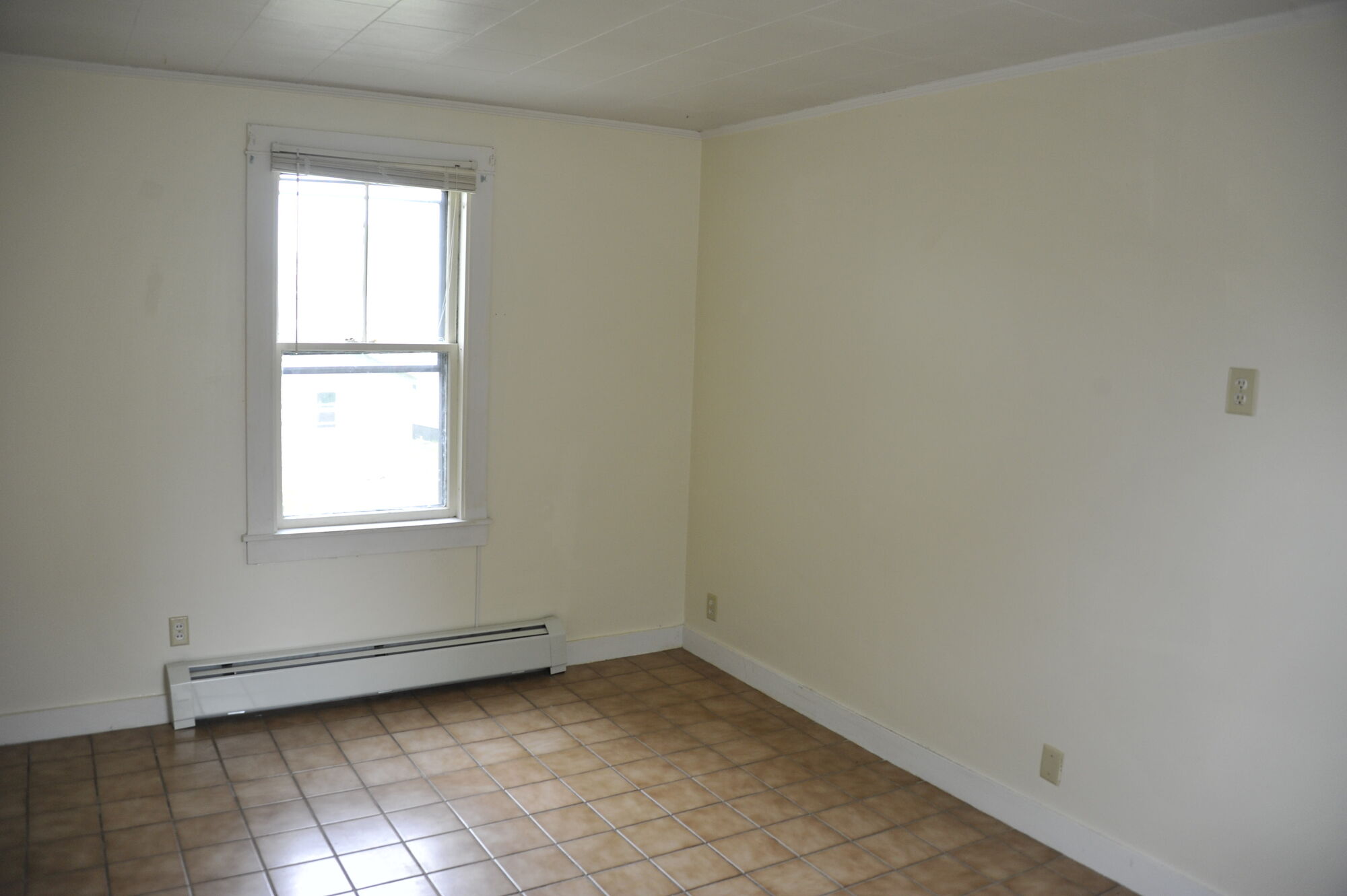 An empty room with tiled floor and bright window